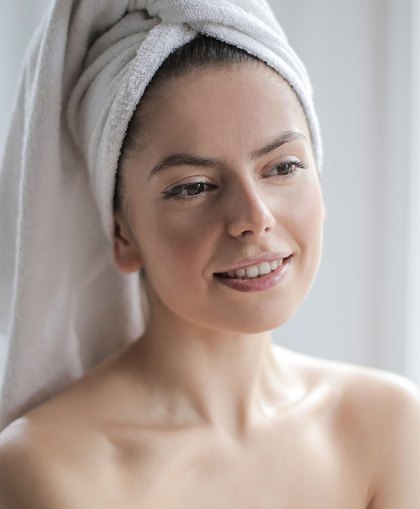 Woman with a towel on her hair smiling after a customized facial