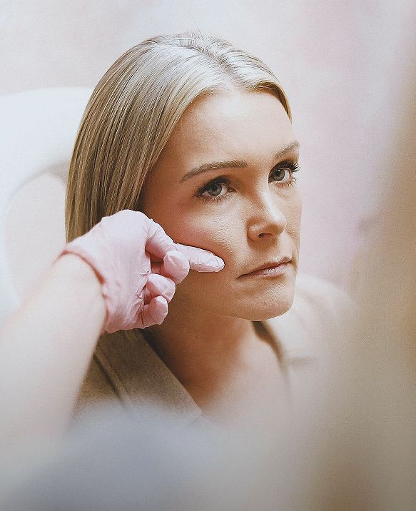 Provider gently examining a client's facial skin during a consultation